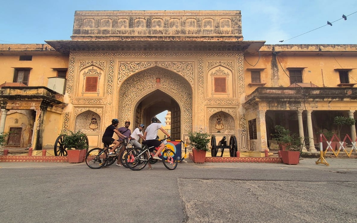 Roads Queen riders cycling past a historic Jaipur gate